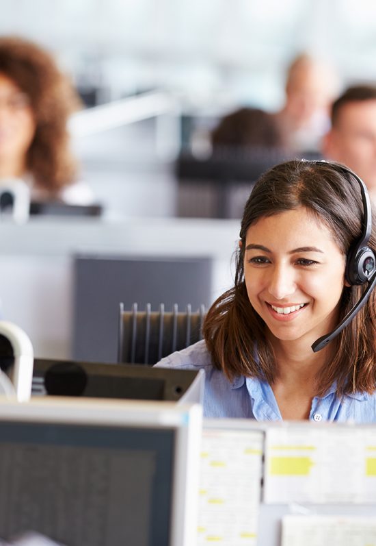 Young woman working in call centre, surrounded by colleagues